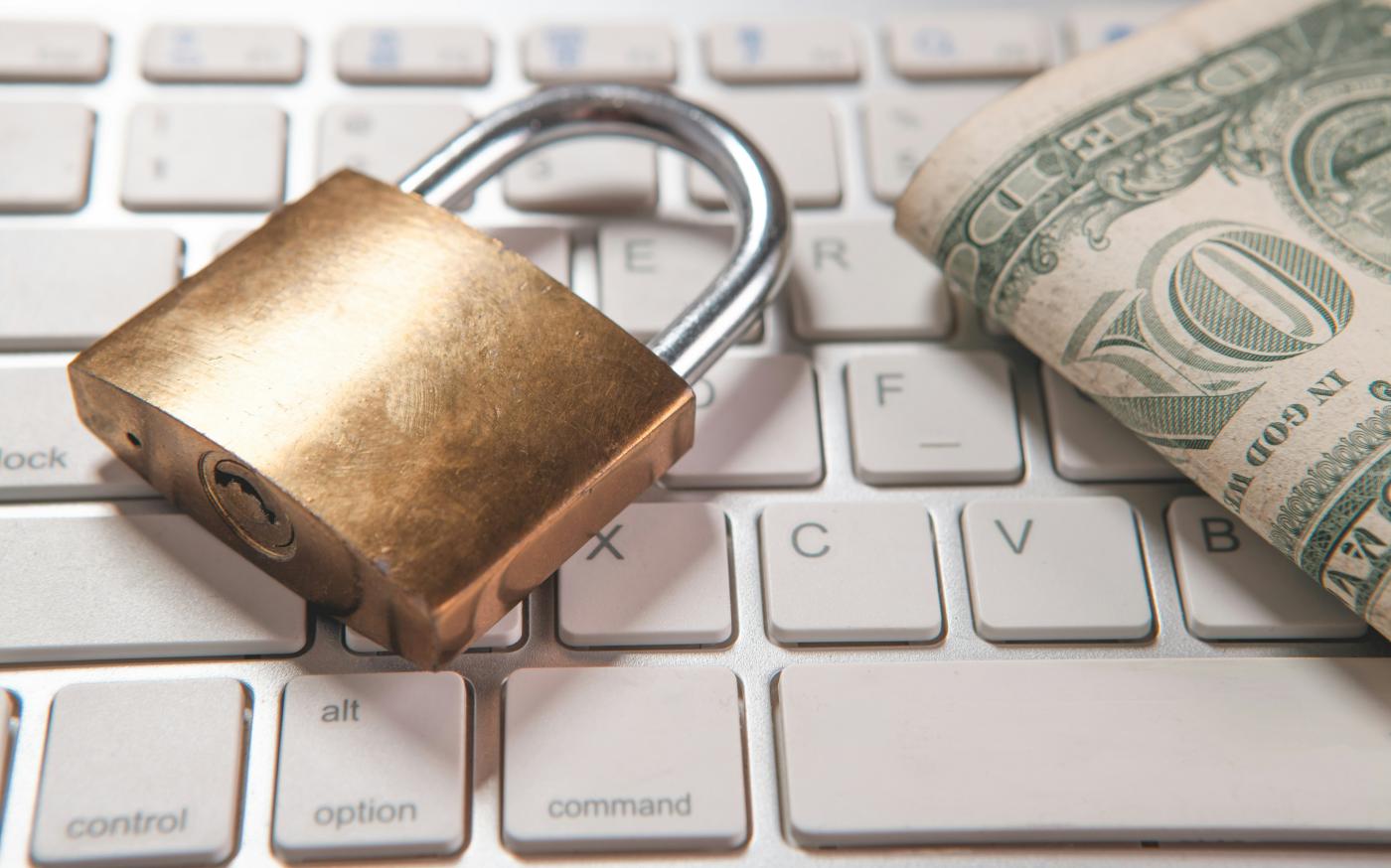 A padlock and dollar bills rest on a computer keyboard. by Sasun Bughdaryan courtesy of Unsplash.