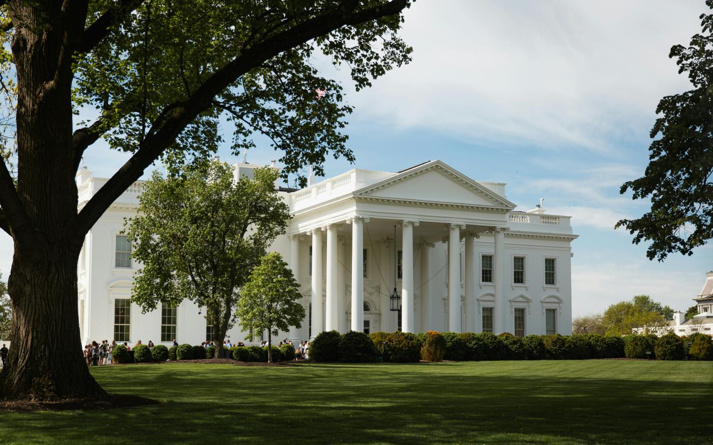 A large white building sitting on top of a lush green field by Benjamin Ashton courtesy of Unsplash.