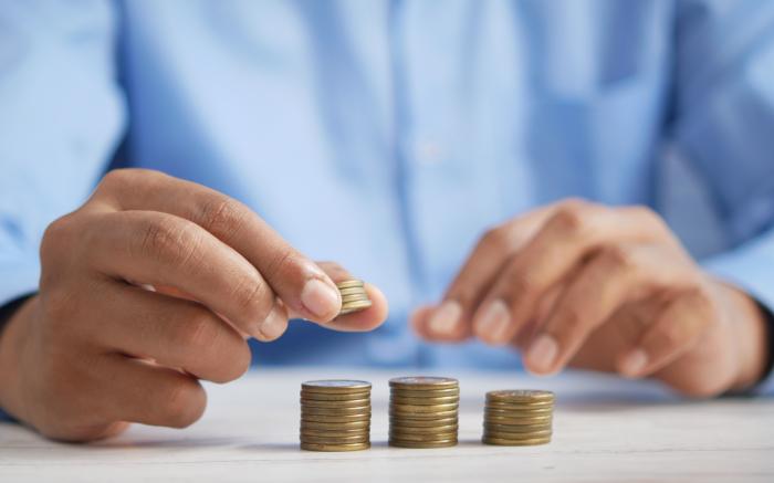 a person stacking coins on top of a table by Towfiqu barbhuiya courtesy of Unsplash.