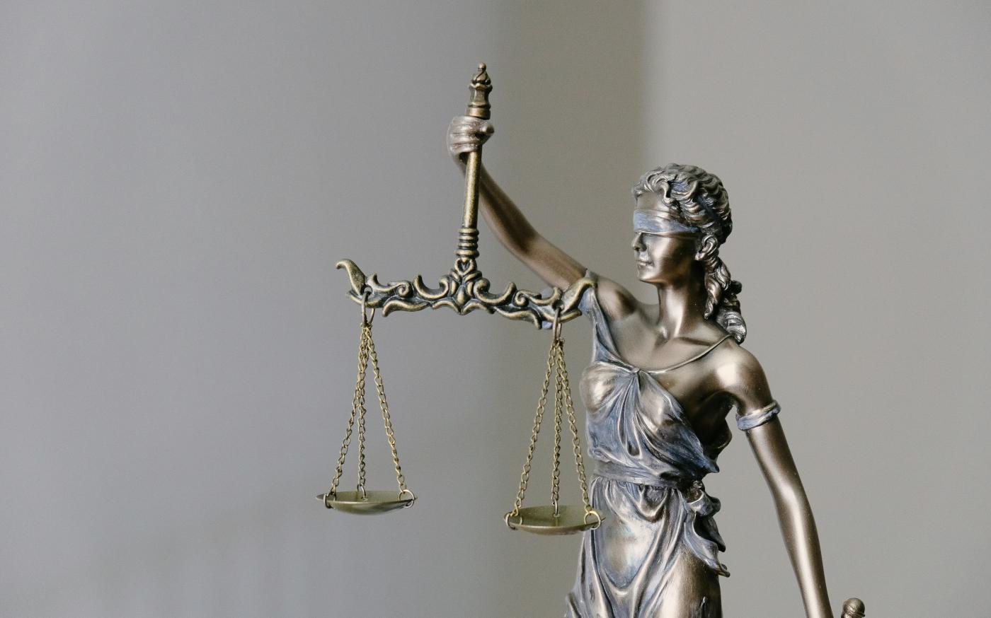 woman in dress holding sword figurine by Tingey Injury Law Firm courtesy of Unsplash.