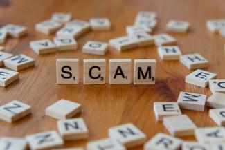 Scam spelled with scrabbles on a wooden table by Markus Winkler courtesy of Unsplash.