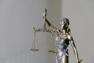 woman in dress holding sword figurine by Tingey Injury Law Firm courtesy of Unsplash.