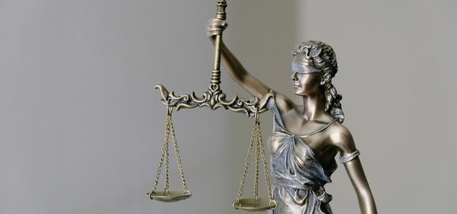 woman in dress holding sword figurine by Tingey Injury Law Firm courtesy of Unsplash.
